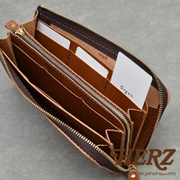 多隔層設計的棕色皮革長夾，內部有數個卡槽和夾層，拉鍊閉合，右下角有品牌標誌HERZ，下方有MADE IN JAPAN Since1973字樣