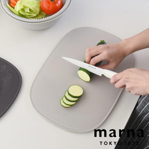 marna TOKYO 1872 品牌標誌，一隻手正在灰色防滑砧板上用白色刀具切櫛瓜，砧板旁有一個裝有蔬菜的白色濾水盆。