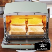 復古風格的淺綠色多用途烤箱，內部有四片吐司正在烘烤，吐司架為銀色金屬網格。