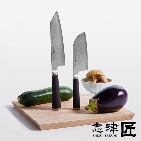 志津匠都 Habahiro 多功能刀，刀身印有日文，旁邊有一根櫛瓜、一個茄子和一碗香菇，擺放在木質砧板上