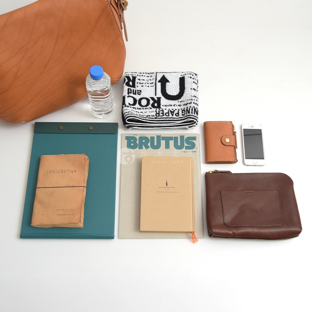 皮革郵差包、水瓶、印有字母的毛巾、筆記本、錢包和手機。