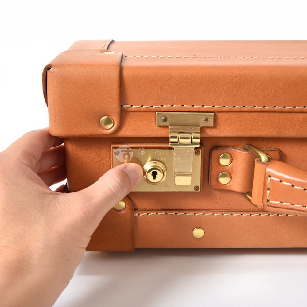 職人手作皮革英倫風便攜手提行李箱，採用棕褐色皮革，配有金色金屬鎖扣、鉚釘和提把，展現經典質感。