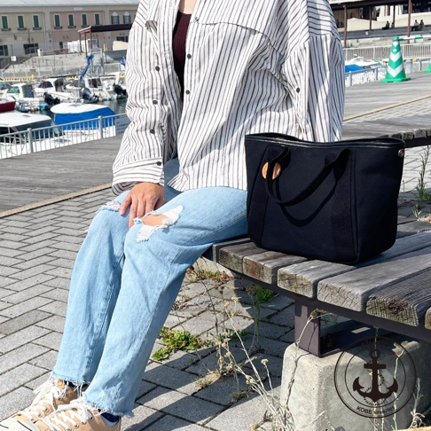 高島帆布多口袋手提托特包，黑色帆布材質，配有皮革提把與木質裝飾，簡約實用。