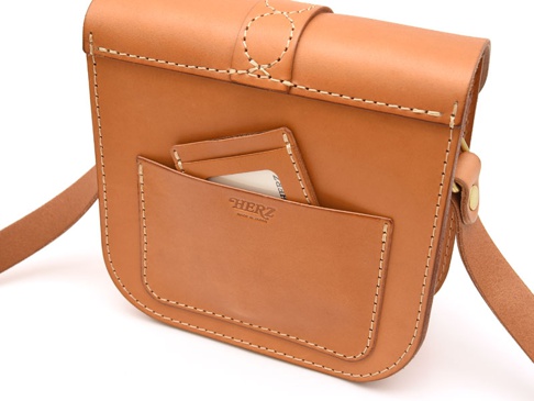 職人手作咖啡色皮革單肩包，正面有兩個開放式口袋，其中一個口袋內插有卡片，包款邊緣及縫線清晰可見，整體呈現自然皮革紋理。