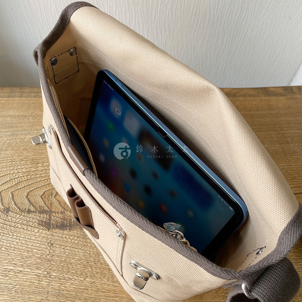犬印純綿帆布雙扣郵差包（米色）內部展示，可放入平板電腦，包包採用帆布材質，配有深棕色滾邊和金屬扣環。