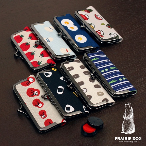 展示一系列和布華印鑑收納口金包，採用各種日式圖案，包括番茄、水藍色蝴蝶結、荷包蛋、壽司、咖啡豆、飯糰和條紋綠葉。口金包為布製，有金屬開合。