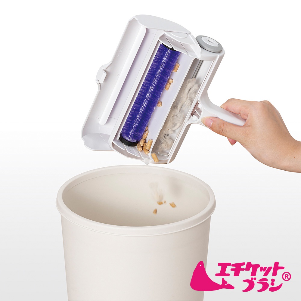 白色塑膠製的免耗材可水洗雙層除塵滾輪，內含藍色刷毛，正在將毛髮和碎屑倒入白色垃圾桶中。