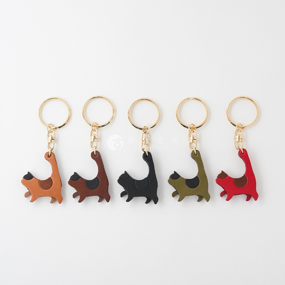 五款職人手作皮革貓咪造型鑰匙圈，顏色包含橘棕、深棕、黑色、軍綠、紅色，每個貓咪造型鑰匙圈都附有金色鑰匙環。