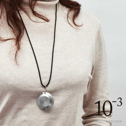 一名女性佩戴著銀色鋁製圓形墜飾，墜飾上有放射狀紋路，由黑色細繩掛著。