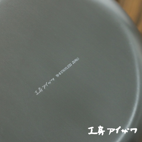 不鏽鋼雙口牛奶鍋，鍋身呈現深灰色，表面有細微的紋理。鍋底印有「18-8 STAINLESS JAPAN」的字樣。