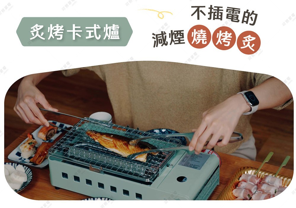一位穿著淺色上衣的人正使用金屬夾，在淺綠色的日本千石阿拉丁卡式爐上翻烤魚片。爐具上方架著烤網，周圍擺放著壽司及培根捲等食材，圖片上方標題寫著不插電的減煙燒烤炙卡式爐，呈現輕鬆的居家料理場景。