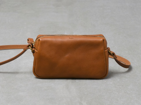 職人手作皮革Organ輕巧拉鍊單肩包，採用棕褐色皮革製成，設有金色拉鍊和可調節的皮革肩帶，包身線條簡潔，設計實用。