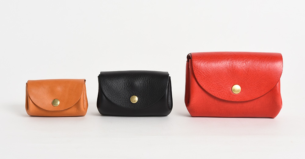 三款不同尺寸的皮革零錢包，分別為棕色、黑色和紅色，皆採用柔軟皮革材質，並配有金色按扣。