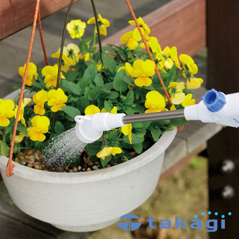 短灑水噴嘴 QG138FJ，白色塑膠與金屬材質，噴灑細緻水霧，正在澆灌一盆盛開的黃色三色堇。