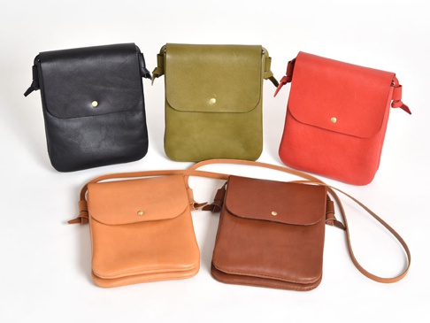 五款職人手作皮革橫式隨行袋，包含黑色、橄欖綠、紅色、淺棕色與深棕色。袋子以皮革製成，設計簡約，附有翻蓋和金屬鈕扣。