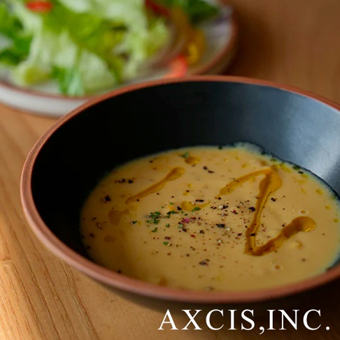 PURE 素燒百搭陶瓷沙拉碗，內裡為黑色，外緣帶有陶土原色，碗中盛有濃稠的黃色湯品，表面淋有橄欖油並撒有香草和黑胡椒粒。