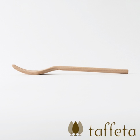 一枚淺色楓木製成的餐叉，有著自然的紋理，叉頭部分向內彎曲，整體呈現簡約的線條。