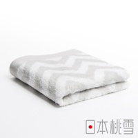 一條淺灰色棉質毛巾，帶有鋸齒狀的白色條紋圖案，毛巾對摺。