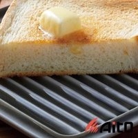 一塊烤至金黃的吐司，上面放著融化的奶油，置於一個帶有條紋的灰色美濃燒吐司酥脆專用盤上。