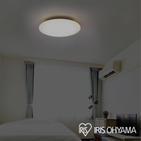 圓盤狀的白色 LED 吸頂燈安裝在天花板上，照亮房間。房間內有窗簾、空調和電視櫃。