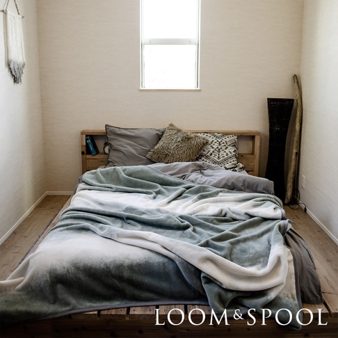 抗菌短絨舒柔雙人毯，採用漸層染設計，以淺綠、灰白為主色調，鋪蓋在木製雙人床上。