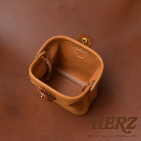 職人手作皮革口金化妝包，淺棕色皮革，內裡為原色皮革，設有金屬按扣，簡約設計，手工縫製。