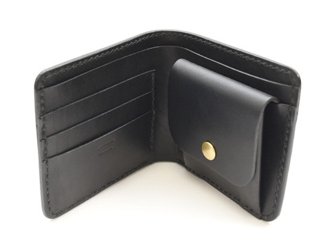 職人手作黑色皮革經典掀蓋扣式雙折短夾，內有四個卡槽與一個帶有黃銅釦的零錢袋。
