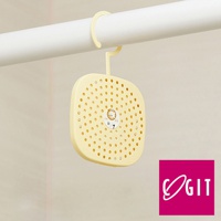 淺黃色方形可掛式除濕除臭貼片盒，表面佈滿圓形透氣孔，中央有圓形指示貼紙，透過掛鉤懸掛在白色橫桿上。