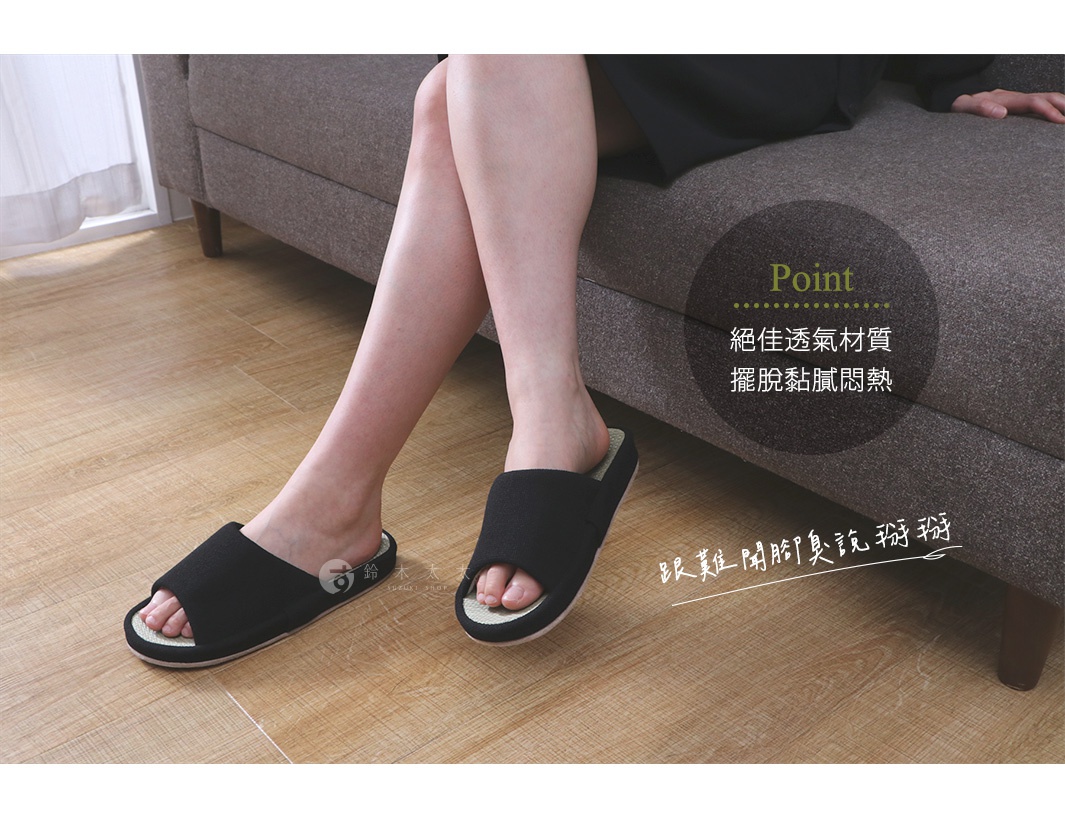 一雙黑色藺草材質的開口式室內拖鞋，鞋底邊緣為淺綠色，適合居家穿著。