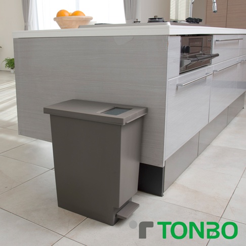 灰色塑膠垃圾桶，具備推蓋和腳踏板設計，頂部有一方形開口，放置於廚房櫥櫃旁。