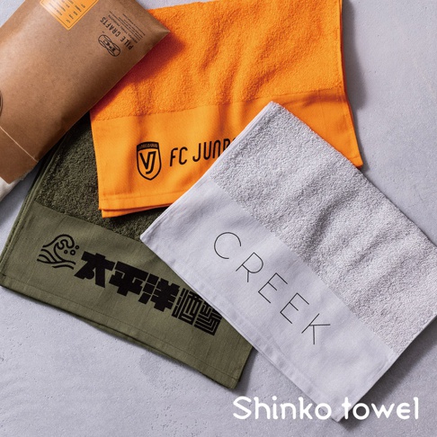 三條毛巾，分別為亮橘色、軍綠色和淺灰色。亮橘色毛巾印有「FC JUNIOR」字樣與標誌，軍綠色毛巾印有波浪圖案與中文「太平洋」字樣，淺灰色毛巾則印有「CREEK」字樣。