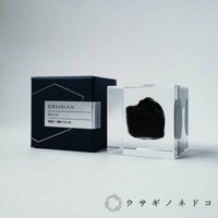 Sola cube Mineral礦石立方塊，內含一塊黑色不規則黑曜石，置於透明立方體中。產品旁有一深藍色禮盒，盒蓋印有「OBSIDIAN」字樣及日文說明。