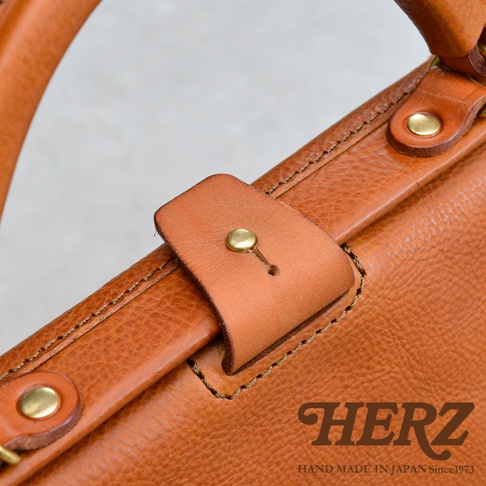 職人手作皮革Organ兩用方形口金托特包，呈現自然棕色皮革紋理，搭配金屬釦與車縫細節，展現品牌HERZ的日式手工質感。