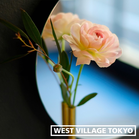 圓形壁掛鏡面漂浮花器，內插一束粉嫩的牡丹花和綠葉，花器為金色金屬材質。