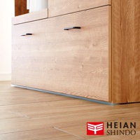 淺色木紋家具底部，裝有黑色長條形把手，下方邊緣處可見一條灰色防倒固定墊，與淺色木地板緊密貼合。