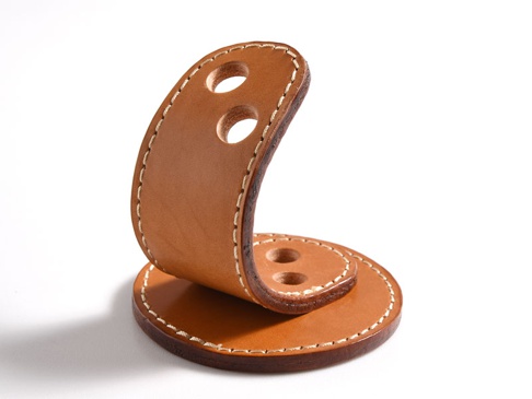 職人手作皮革兩入用筆架，原色皮革，圓形底座上立起一條彎曲的皮革，兩處各打有兩個圓孔，以白色縫線手工縫製。