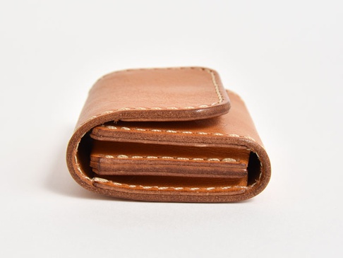 職人手作皮革雙折收納零錢包，淺棕色皮革，以白色縫線手工縫製，呈現簡約雙折結構，可見多層皮革夾層。