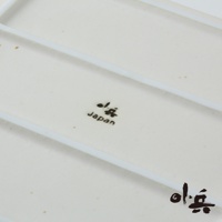 米白色的美濃燒油切方盤，盤面有黑色日文標誌及「Japan」字樣，盤底右側有黑色日文標誌。