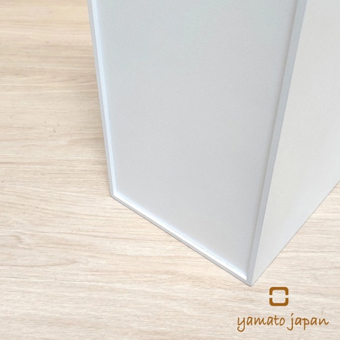 白色前開式隙縫可堆疊垃圾桶的局部特寫，展示其簡約設計和淺木色背景。