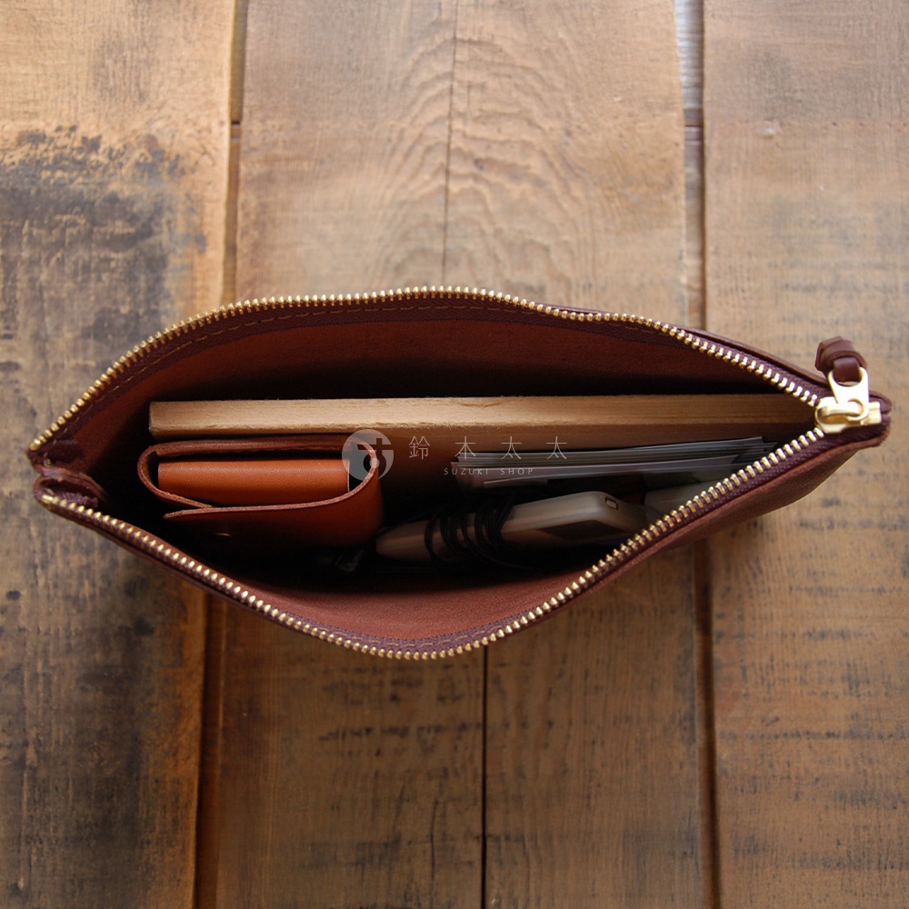 職人手作皮革Organ拉鍊式小物收納袋，棕色皮革，內含筆記本、皮夾、手機及其他小物，拉鍊為金色。