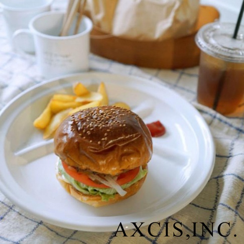 白色琺瑯分隔餐盤，盤中盛有漢堡、薯條和番茄醬，餐盤旁有一杯冰飲。