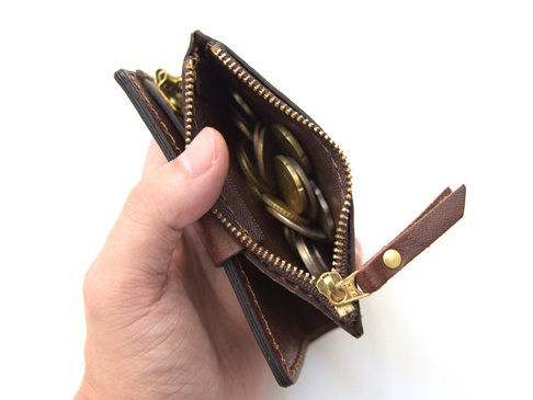 職人手作的深棕色皮革零錢鑰匙包，拉鍊開口，內有零錢和四個鑰匙鉤，拉鍊頭為金色，附有皮革拉帶。