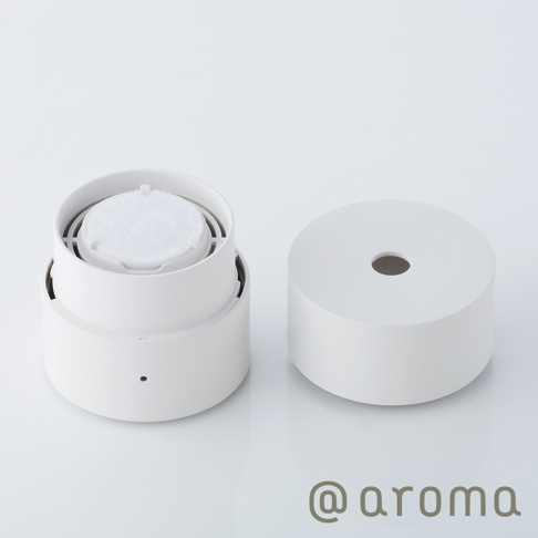 白色圓柱形替補棉片，置於打開的香氛機組件中，另一半圓柱形外蓋並排。