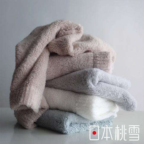 堆疊的五條柔軟毛巾，顏色由淺至深分別為淺駝色、粉色、淺灰色、白色和深灰色，背景為白色。