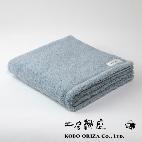 一張淡藍色的今治柔感浴巾，採用匹馬棉材質，整齊摺疊於白色背景前，浴巾表面可見細緻的織紋。