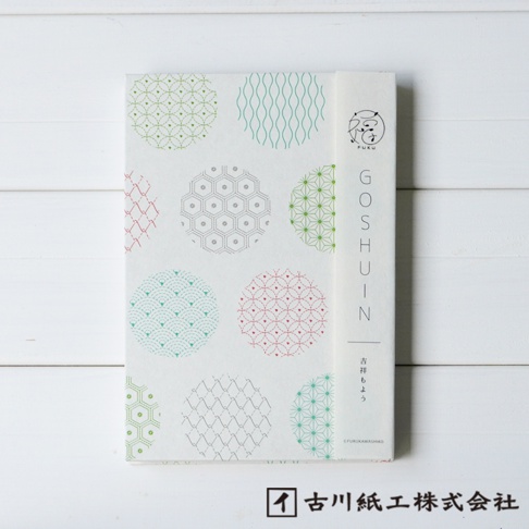 美濃和紙製福氣御朱印帳，封面以白色為底，印有綠色、藍綠色、紅色、灰色等多種色彩的吉祥圖案，圖案以圓形分區，包含波紋、網格、菱形等設計。右側書寫著「GOSHUIN」字樣及日文「吉祥もよう」，並有「FUKU」標誌。