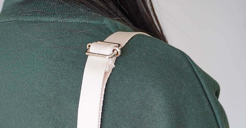 一名女子肩上佩戴著一個米白色織帶肩帶，織帶上裝有銀色金屬調節環。