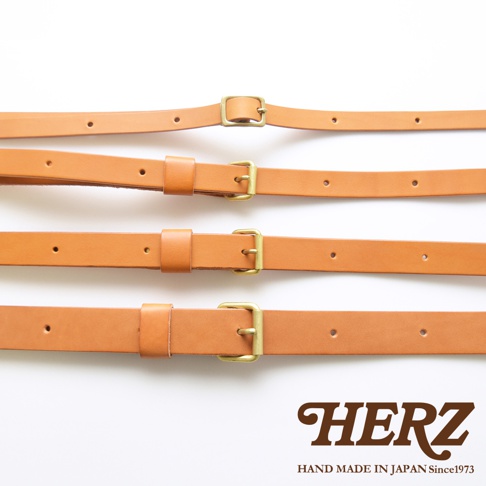 四條淺棕色皮革製成的肩背帶，每條皆配有金色金屬扣環及調節孔，下方有HERZ品牌標誌與手工製作於日本的字樣。