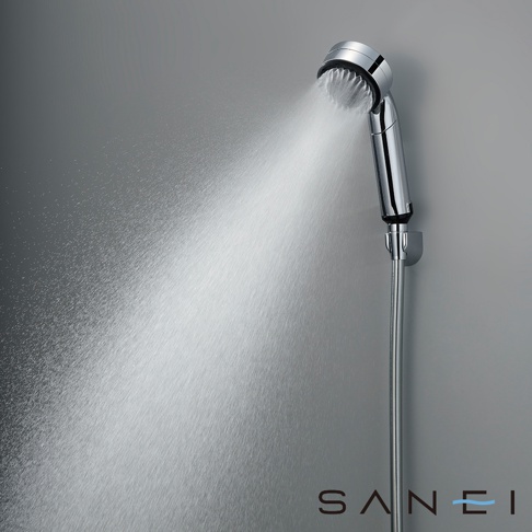 銀色金屬蓮蓬頭，噴出細緻的水霧，蓮蓬頭上有白色濾網，連接金屬軟管，固定於灰色牆壁上。