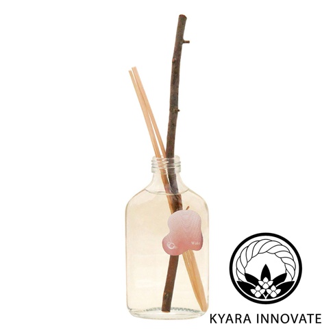KYARA INNOVATE 品牌標誌旁，一個玻璃瓶裝著透明擴香液，瓶內有深色樹枝及淺色擴香竹，瓶身貼有粉色橢圓形標籤，標籤上印有「Wake」字樣
